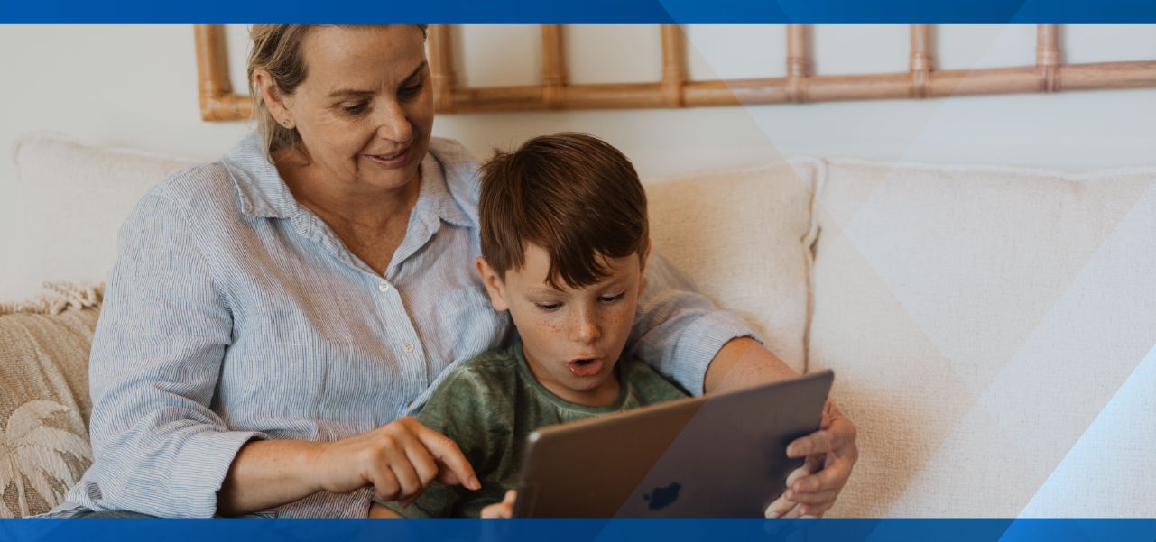 an older lady sitting on the couch with a young chilld looking at a device